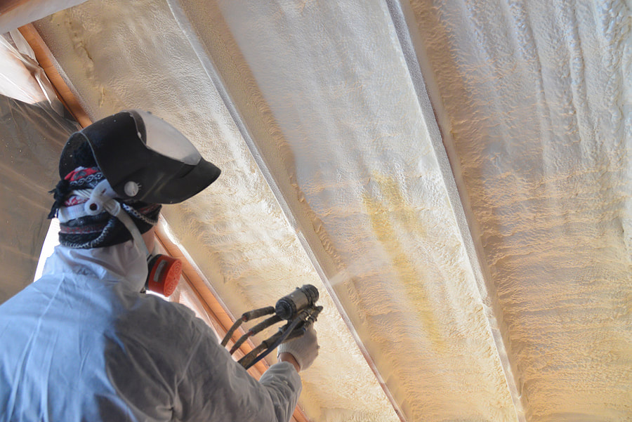 worker spraying insulation in the wall